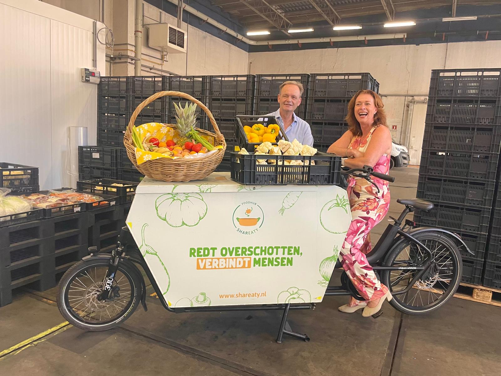 Oprichter Berend Maten en Mariette van Leeuwen, gedeputeerde Provincie Zuid-Holland bij de bakfiets waarmee veel voedsel in de wijk Feijenoord wordt rondgebracht.